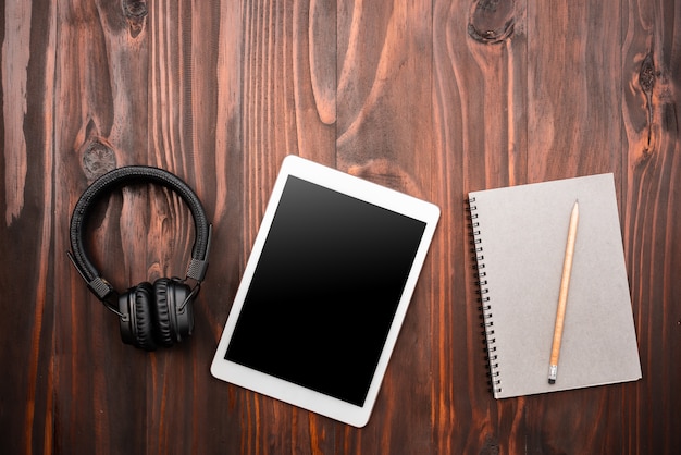 Foto tela em branco do tablet digital e fone de ouvido na vista de topo de mesa de trabalho