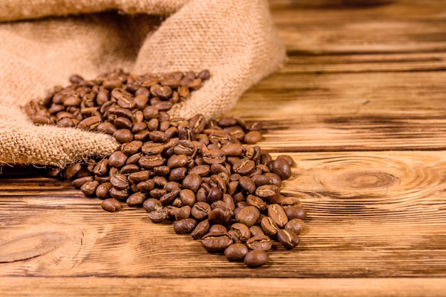 Tela de saco y granos de café dispersos en la mesa de madera