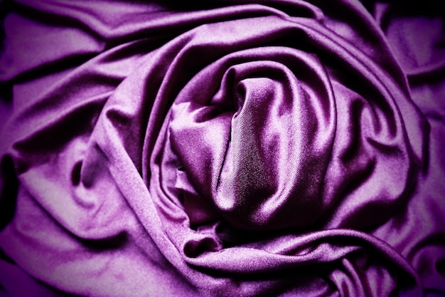 Foto tela de terciopelo similar a la seda textiles en pliegues hermosas ondas retorcidas en un círculo tonos púrpura rosa magenta en las cortinas material de costura para vestidos tapicería de muebles cortinas
