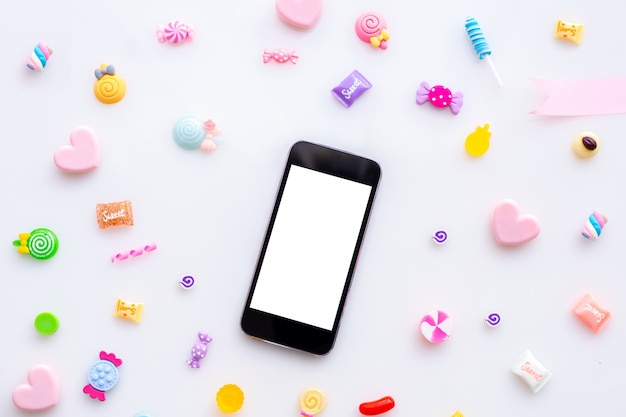 Tela vazia no telefone celular do smartphone, tabuleta com os doces doces no fundo branco.