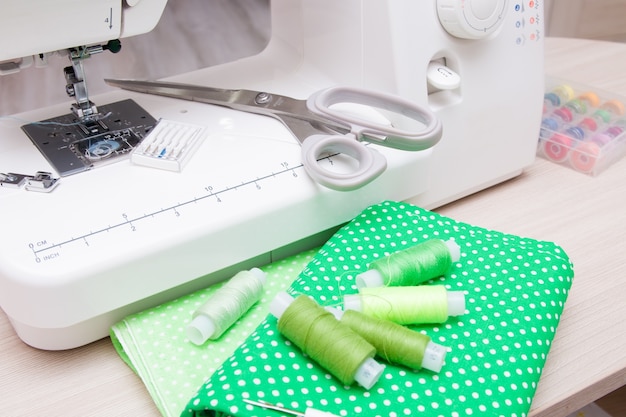 telas, máquina de coser, tijeras y carretes de hilo sobre la mesa