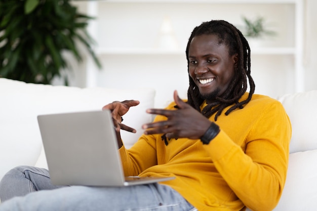 Teleconferência sorrindo homem afro-americano fazendo videochamada no laptop em casa