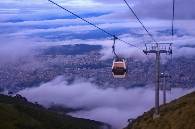 El teleférico aéreo contra el paisaje urbano en tiempo de niebla