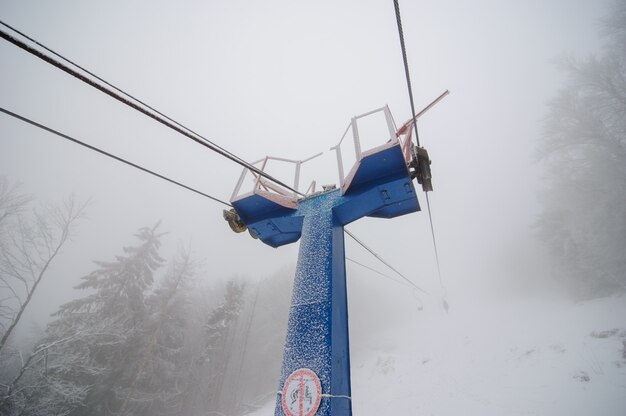 Teleférico até a montanha na floresta de inverno. a floresta está coberta de neve. tempo de nevoeiro. má visibilidade.