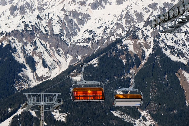 Teleférico com neve e árvores debaixo do céu azul ensolarado