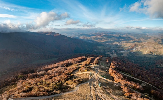 Teleférico no cume da colina e pistas de esqui ao longo das encostas das montanhas