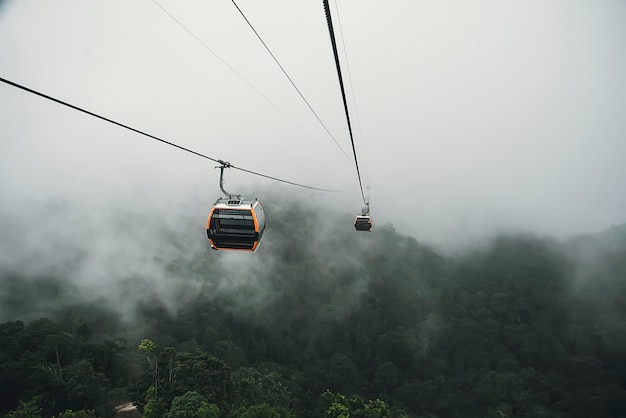 Teleférico subindo a colina nebulosa sobre floresta espessa em Banahill Danang Vietnam