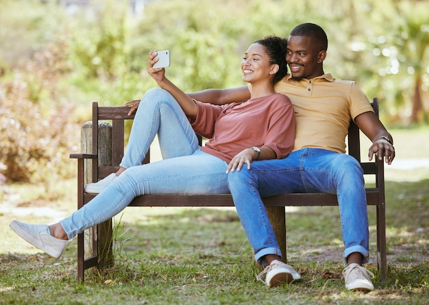 Telefon entspannen oder ein Paar, das ein Selfie in einem Park für ein schönes Date in einer natürlichen Umgebung für frische Luft macht Naturprofilbild oder glückliche schwarze Frau, die Social-Media-Bilder mit einem schwarzen Mann macht