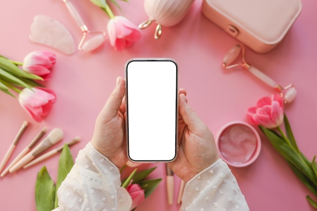 Telefon in Händen mit einem isolierten Bildschirm auf dem Hintergrund von Kosmetika ein Platz für Ihren Text