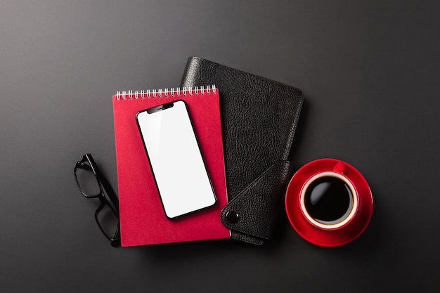 Telefon und Notizblöcke auf dem Desktop mit einer Tasse Kaffee, in sozialen Netzwerken arbeiten, in einen Notizblock schreiben. Von oben betrachten. Foto in hoher Qualität