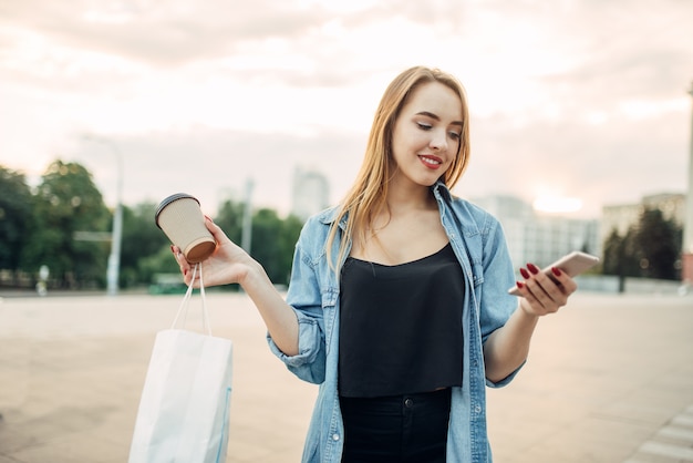 Telefonabhängige Frau hält Gerät und Kaffee in der Hand