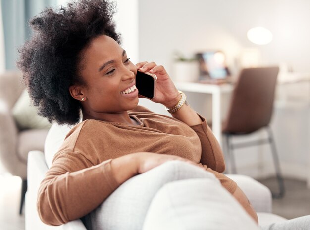 Telefonanruf Entspannen Sie sich und lächeln Sie mit einer schwarzen Frau im Wohnzimmer ihres Hauses, die auf einem Sofa sitzt, während sie spricht Mobile Kommunikation und Konversation mit einer jungen Frau, die in ihrem Haus chattet