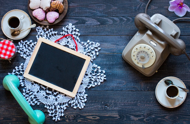 Telefone antigo vintage, com biscoitos, caffè, rosquinhas numa superfície de madeira,