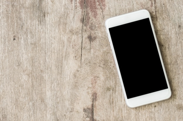 Telefone celular branco em uma mesa de madeira