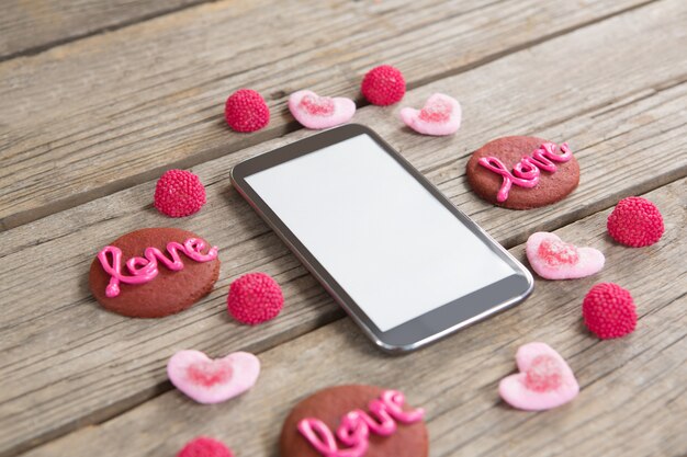 Telefone celular cercado por biscoitos e confeitaria