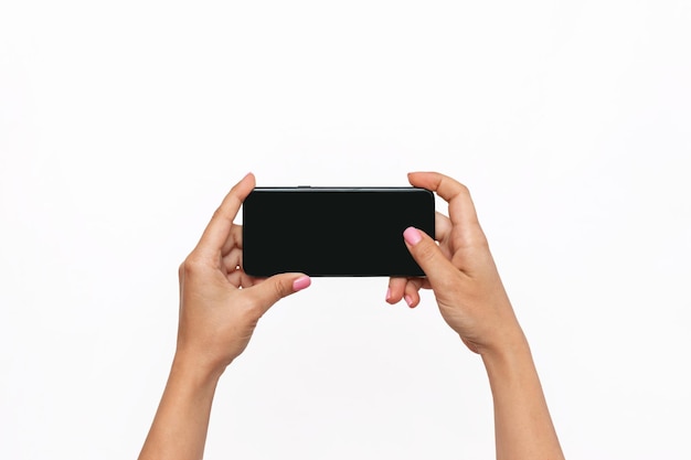 Telefone celular com tela preta nas mãos isoladas em um fundo branco Uma jovem tira foto