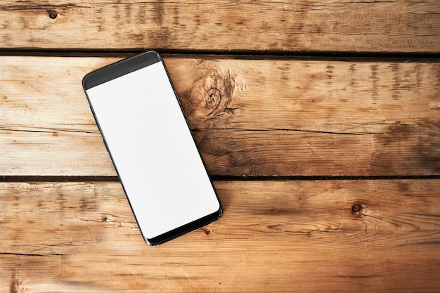Telefone celular com uma tela em branco em uma mesa de madeira