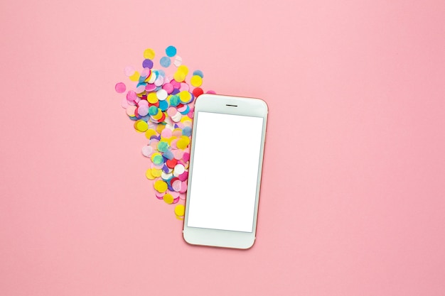 Telefone celular e confetes coloridos na tabela pastel rosa no estilo plana leigos