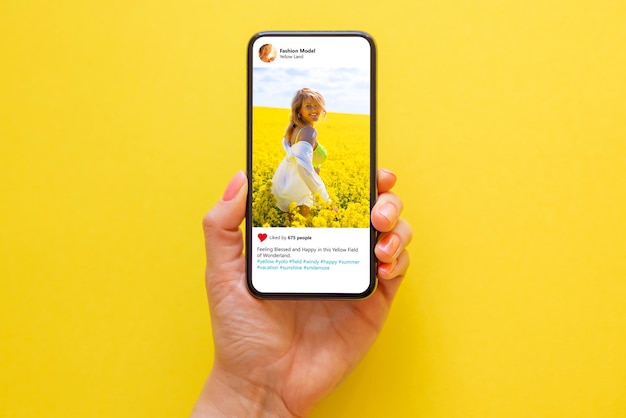 Telefone celular em fundo amarelo com foto de mulher em prado amarelo na tela
