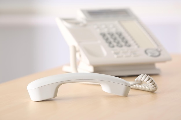 Telefone com receptor atendido na mesa de madeira no escritório