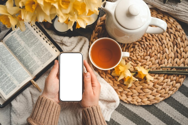 Telefone com uma tela isolada nas mãos contra o fundo da Bíblia composição estética de primavera