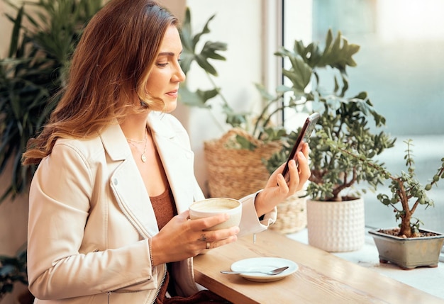 Telefone de cafeteria e comunicação com uma cliente bebendo enquanto digita uma mensagem de texto em uma janela Internet café móvel e mídia social com uma mulher desfrutando de uma bebida em um restaurante