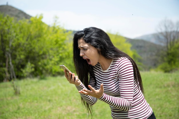 Telefone de mão de mulher irritada na natureza