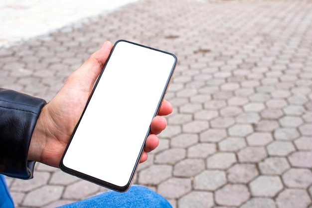 Telefone de maquete. Mão segurando o smartphone ao ar livre.