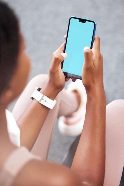 Telefone de tela verde e mulher negra no aplicativo digital para exercícios físicos e rastreamento de academia Maquete móvel em branco com um atleta na internet da web e rolagem de mídia social no clube de saúde na rede social