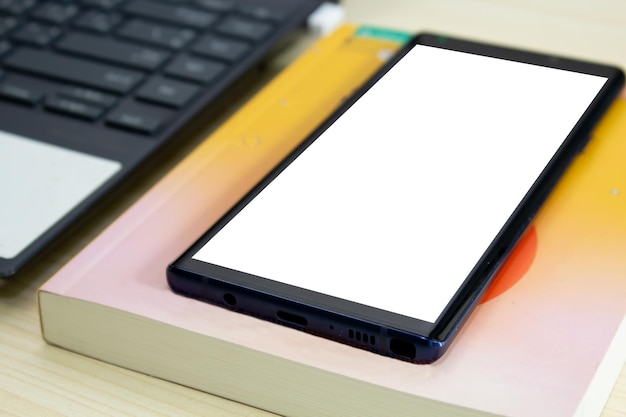 Telefone inteligente com livro e computador e notebook estão em uma mesa