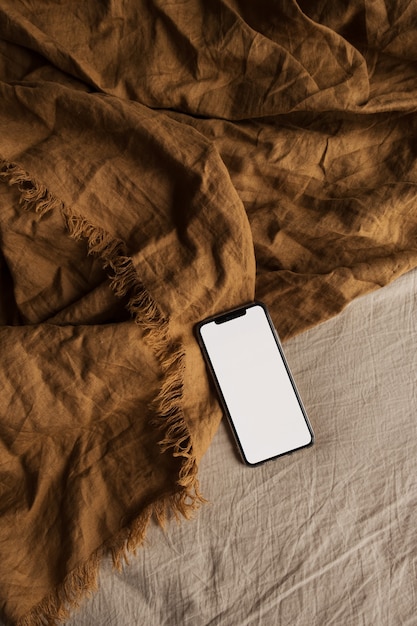 Telefone inteligente de tela em branco no cobertor de gengibre.