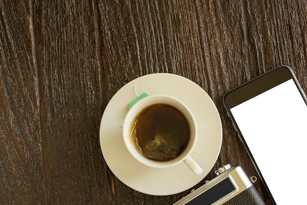 Telefone inteligente e câmera com chá quente na mesa de madeira