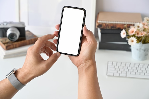 Telefone inteligente móvel na mão do homem no trabalho de mesa.