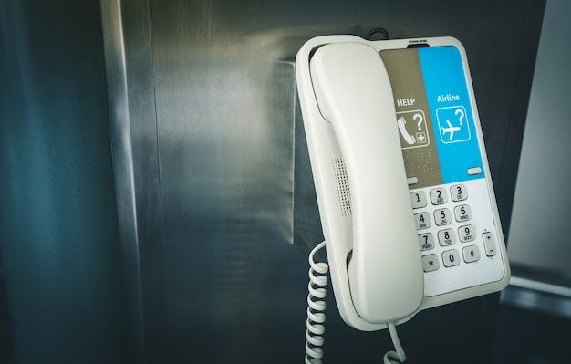 Foto telefone interno que pendura em um polo no aeroporto internacional para o auxílio e a ajuda.