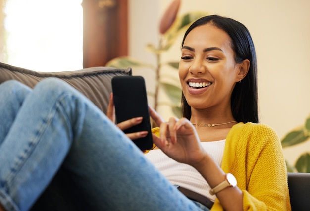 Foto telefone relaxe e mulher rindo na sala de estar de casa no sofá mídia social ou meme engraçado comédia de celular e pessoa feliz rolagem na web navegação on-line ou mensagens de texto para piada em casa