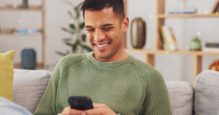 Foto telefone rindo e relaxe com o homem no sofá para internet de mídia social e mensagem de texto sorriso feliz e tecnologia com homem na sala de estar em casa para conexão de comunicação e aplicativo digital