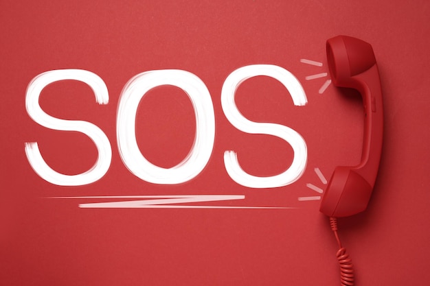 Telefonhörer auf rotem Hintergrund Draufsicht SOS-Notruf