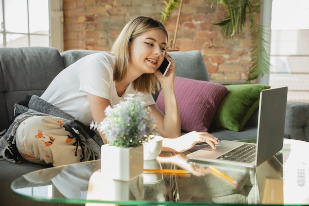 Telefonieren. Kaukasische Frau, Freiberuflerin während der Arbeit im Homeoffice während der Quarantäne. Junge Geschäftsfrau zu Hause, selbst isoliert. Verwenden von Geräten. Fernarbeit, Prävention der Ausbreitung von Coronaviren.