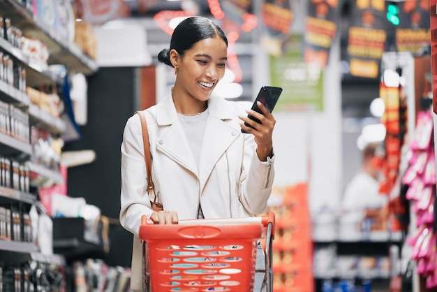 Teléfono 5g Internet y compras de comestibles Mujer india leyendo un texto divertido o contenido de redes sociales Cómic web móvil y desplazamiento en línea en una tienda minorista de alimentos con una sonrisa de cliente feliz de India