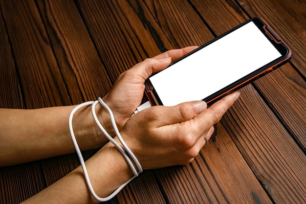 Foto teléfono con adicción a las manos sobre una superficie de madera