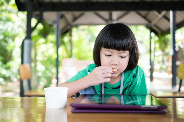 Teléfono adicto al niño chino, niña asiática jugando teléfono inteligente, niño viendo dibujos animados