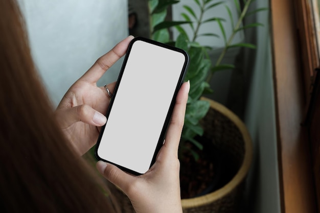 teléfono celular pantalla blanca en blanco maqueta mujer con la mano enviando mensajes de texto usando móvil en el escritorio de la oficina en el fondo espacio vacío para publicidad