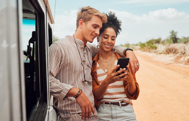 Teléfono de coche y pareja en un viaje por carretera en verano de vacaciones para disfrutar viajando y compartiendo noticias en las redes sociales Naturaleza interracial y mujer feliz buscando en el mapa gps con una pareja tranquila en vacaciones