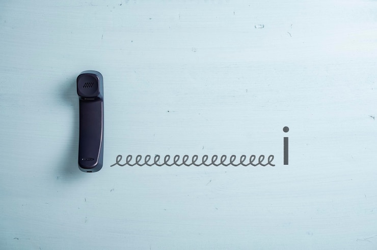 Foto teléfono fijo negro conectado a una letra i por un cable dibujado a mano