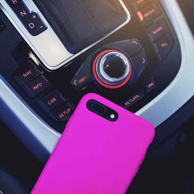 Teléfono en funda rosa con doble cámara en el interior de un coche moderno