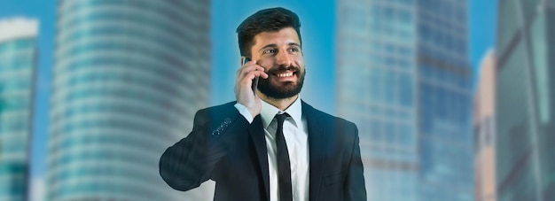 El teléfono del hombre cerca de la ventana en el fondo de un rascacielos