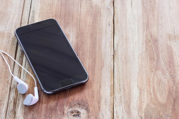 El teléfono inteligente y los auriculares yacen en madera vieja