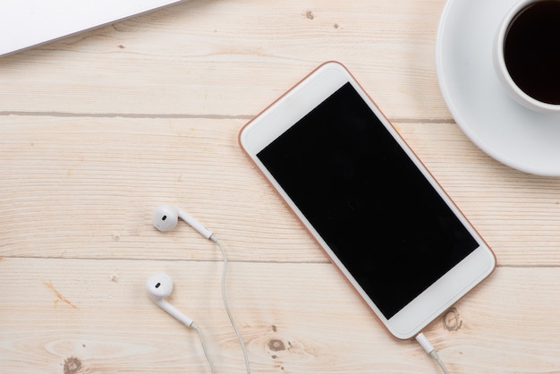 Teléfono inteligente blanco con escritorio acostado de pantalla en blanco