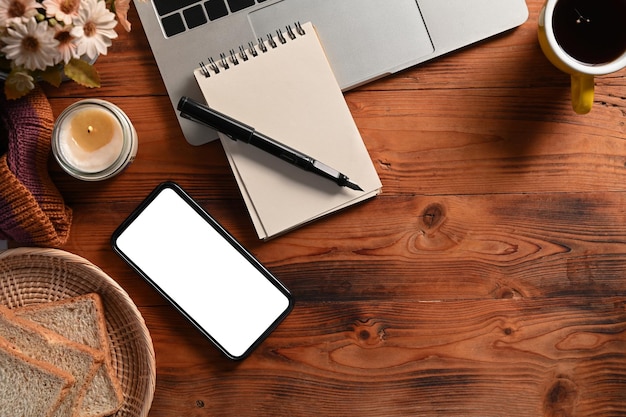 Teléfono inteligente computadora portátil vela portátil y taza de café en la mesa de madera