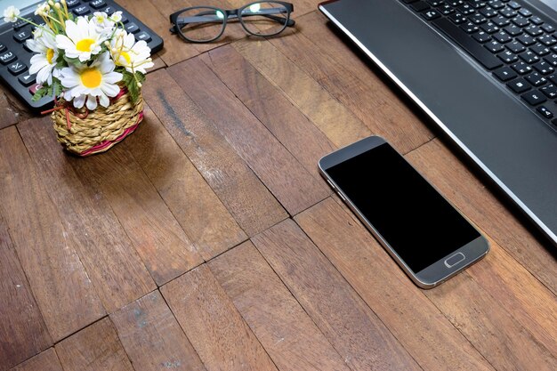 Foto teléfono inteligente y equipos de oficina en una mesa de madera